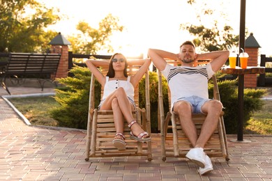 Couple resting together in deck chairs outdoors