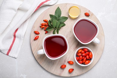 Photo of Fresh rose hip tea and berries on light table, flat lay