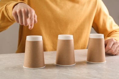 Photo of Man playing shell game at light marble table, closeup