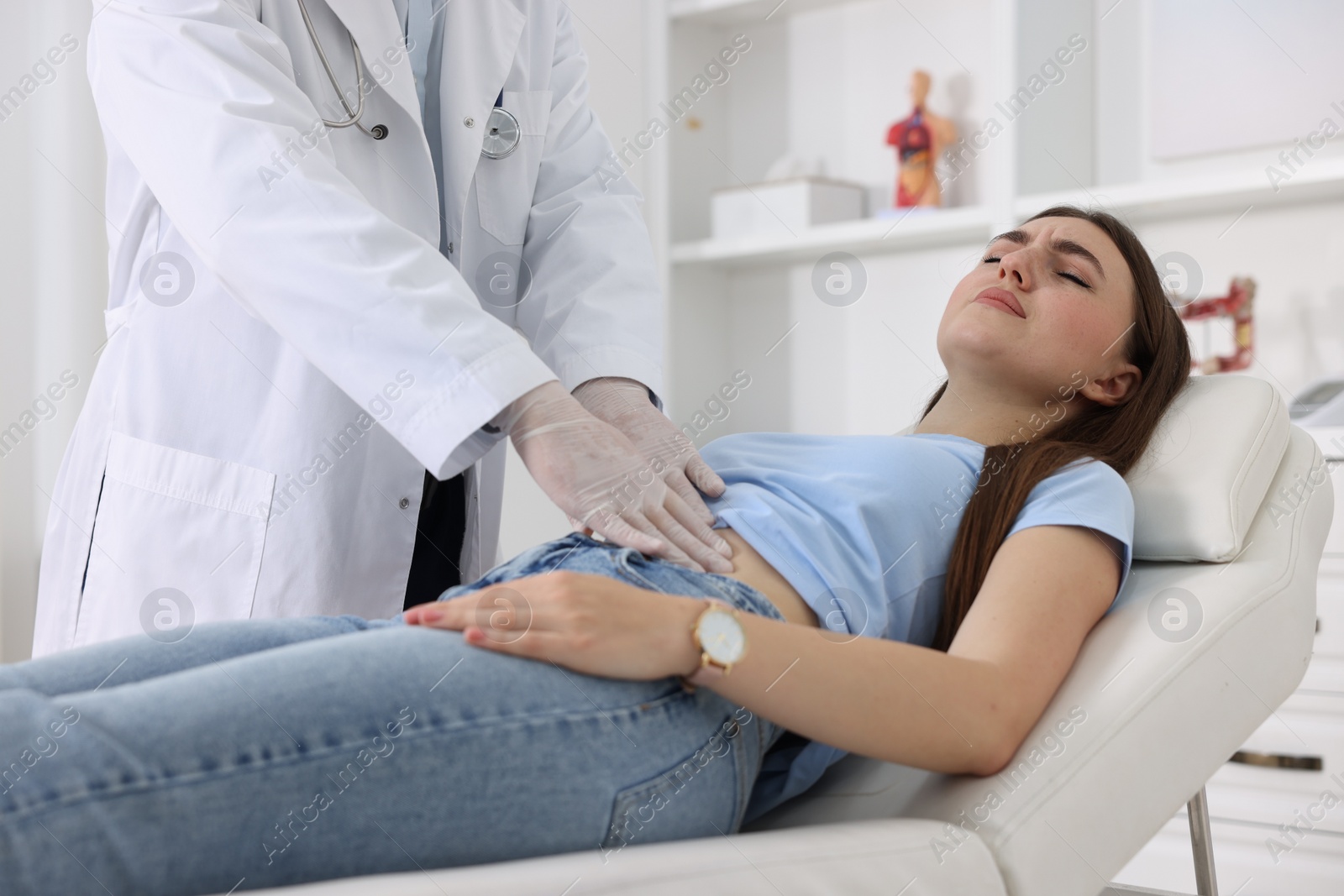 Photo of Gastroenterologist examining patient with stomach pain on couch in clinic, closeup