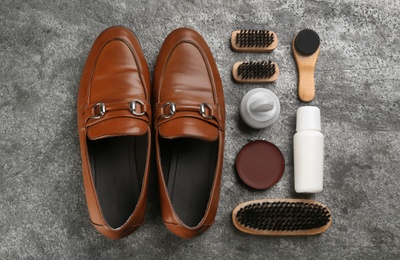 Photo of Flat lay composition with shoe care accessories and footwear on grey stone background