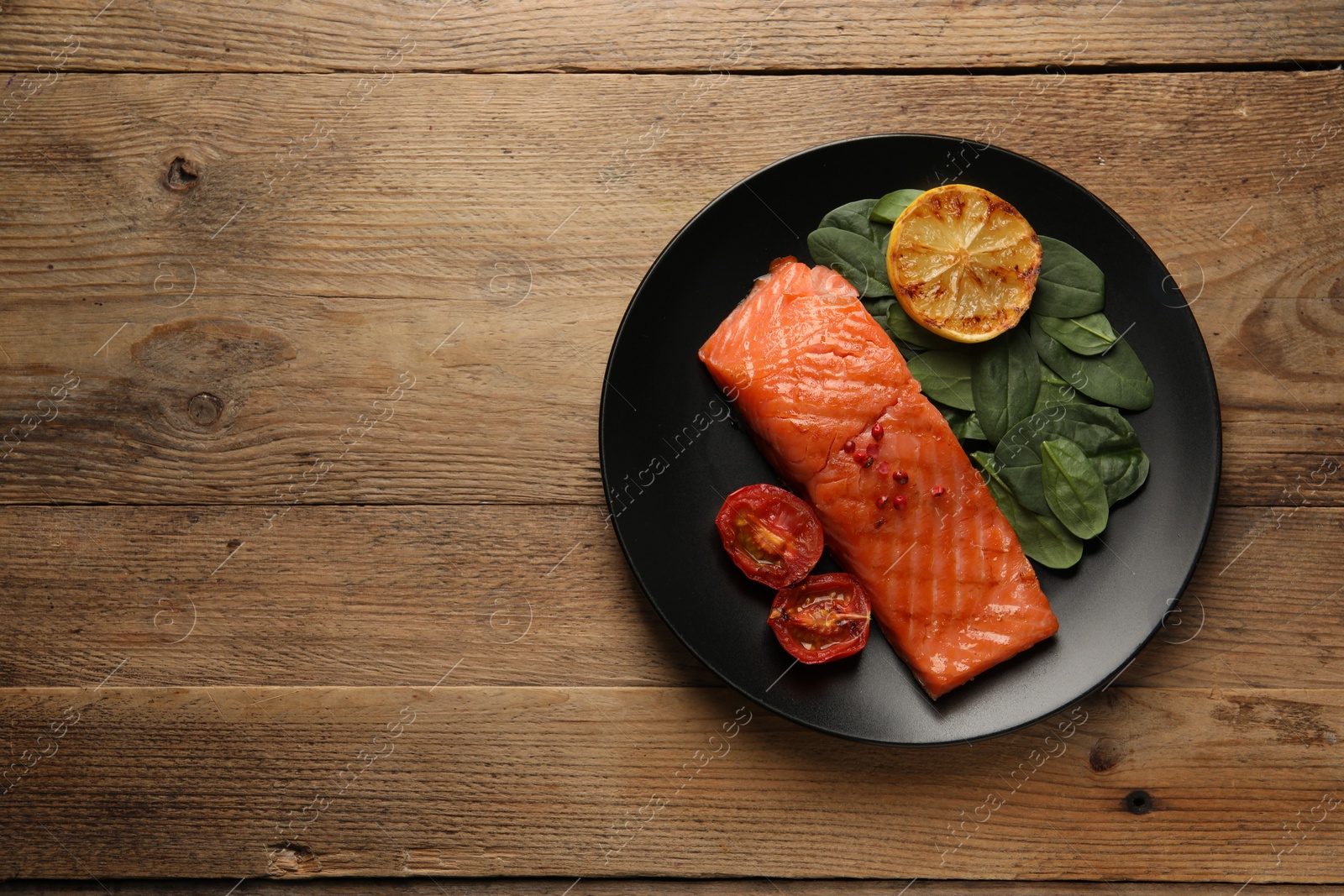 Photo of Tasty grilled salmon with tomatoes, lemon and basil on wooden table, top view. Space for text