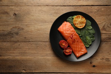 Photo of Tasty grilled salmon with tomatoes, lemon and basil on wooden table, top view. Space for text