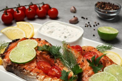 Photo of Tasty grilled salmon steaks and ingredients on light grey table, closeup