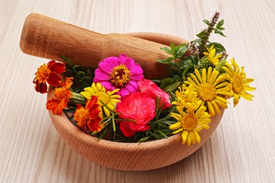 Photo of Mortar with pestle and beautiful fresh flowers on wooden table