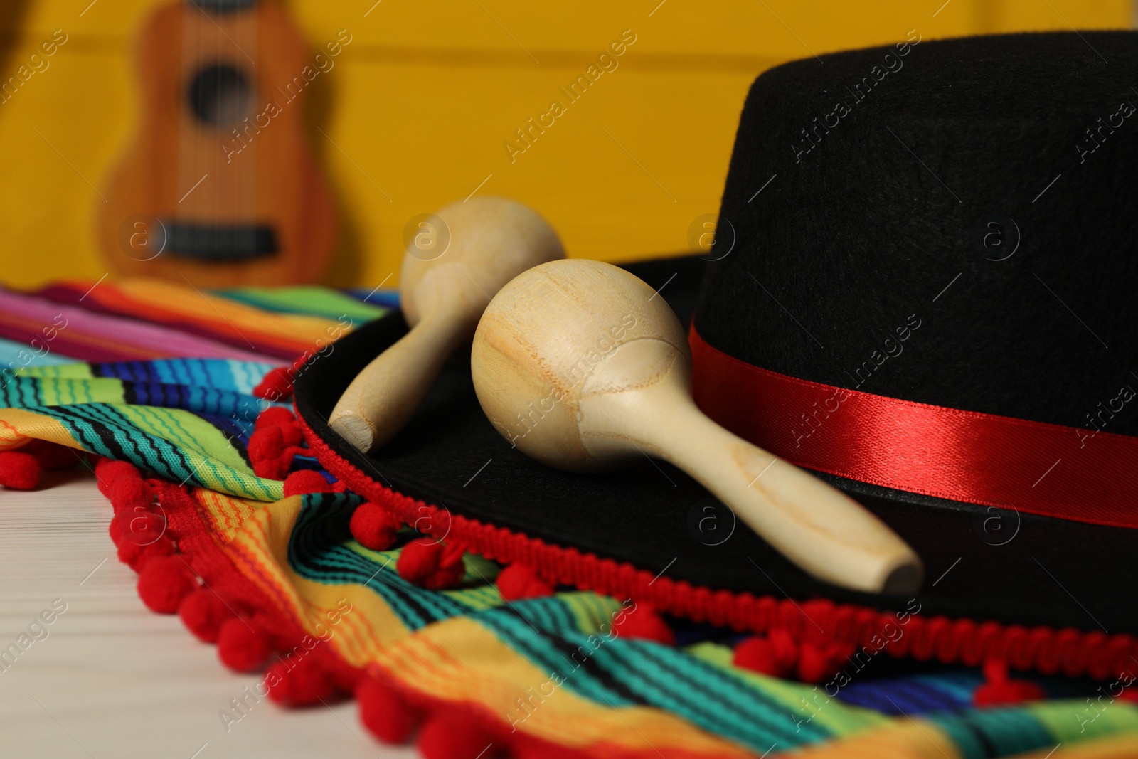 Photo of Black Flamenco hat, poncho and maracas on light table, closeup