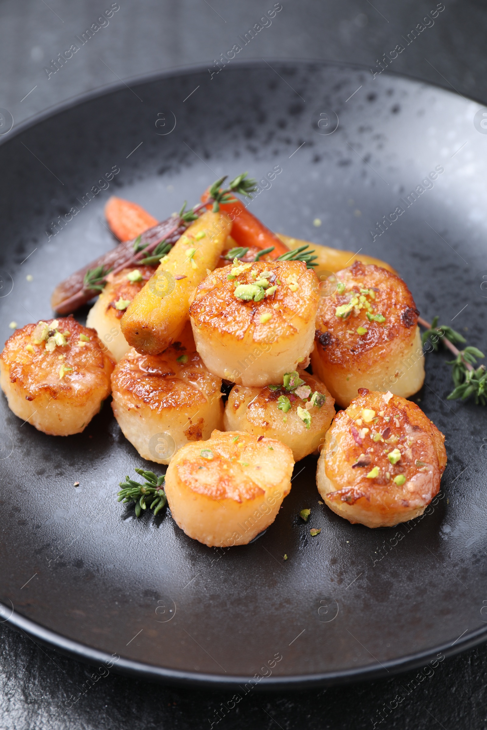 Photo of Delicious fried scallops on dark textured gray table, closeup