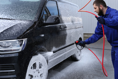 Worker covering automobile with foam at car wash