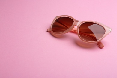 Photo of Stylish sunglasses on pink background, space for text. Fashionable accessory