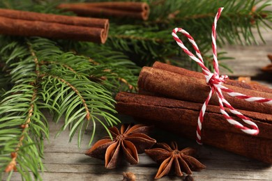 Photo of Different spices and fir branches on wooden table, closeup