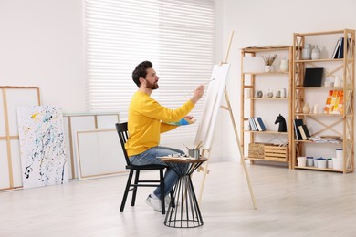 Man painting in studio. Using easel to hold canvas