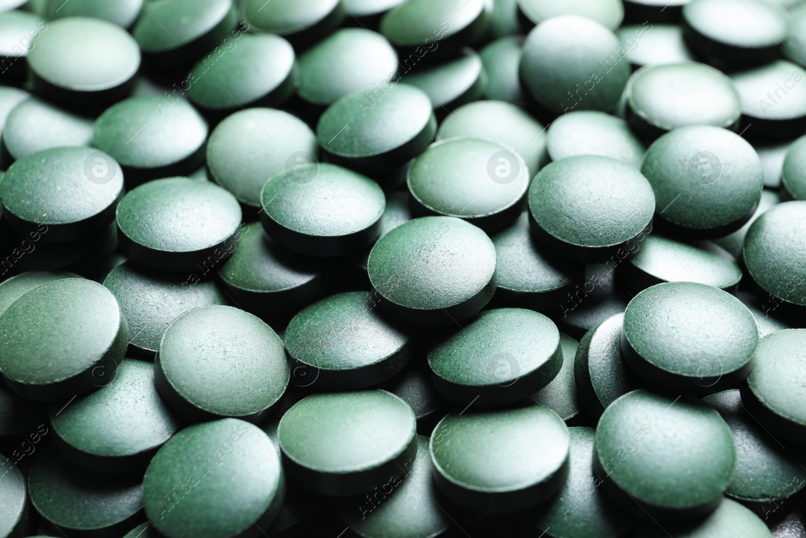 Photo of Green spirulina pills as background, closeup view