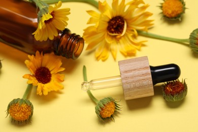 Photo of Bottle and pipette with essential oil near beautiful calendula flowers on yellow background, closeup