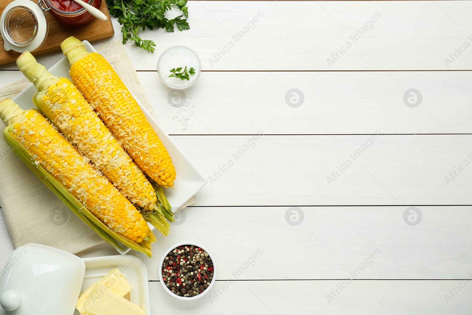 Photo of Plate with tasty cooked corn cobs on white wooden table, flat lay. Space for text