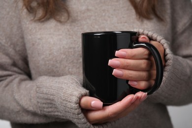 Photo of Woman holding black ceramic mug, closeup view