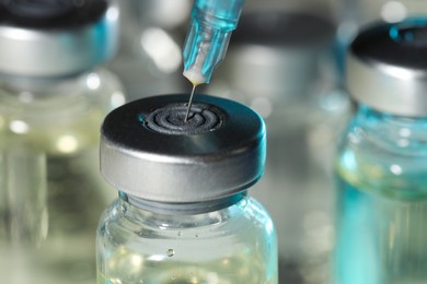 Photo of Filling syringe with medicine from vial against blurred background, closeup