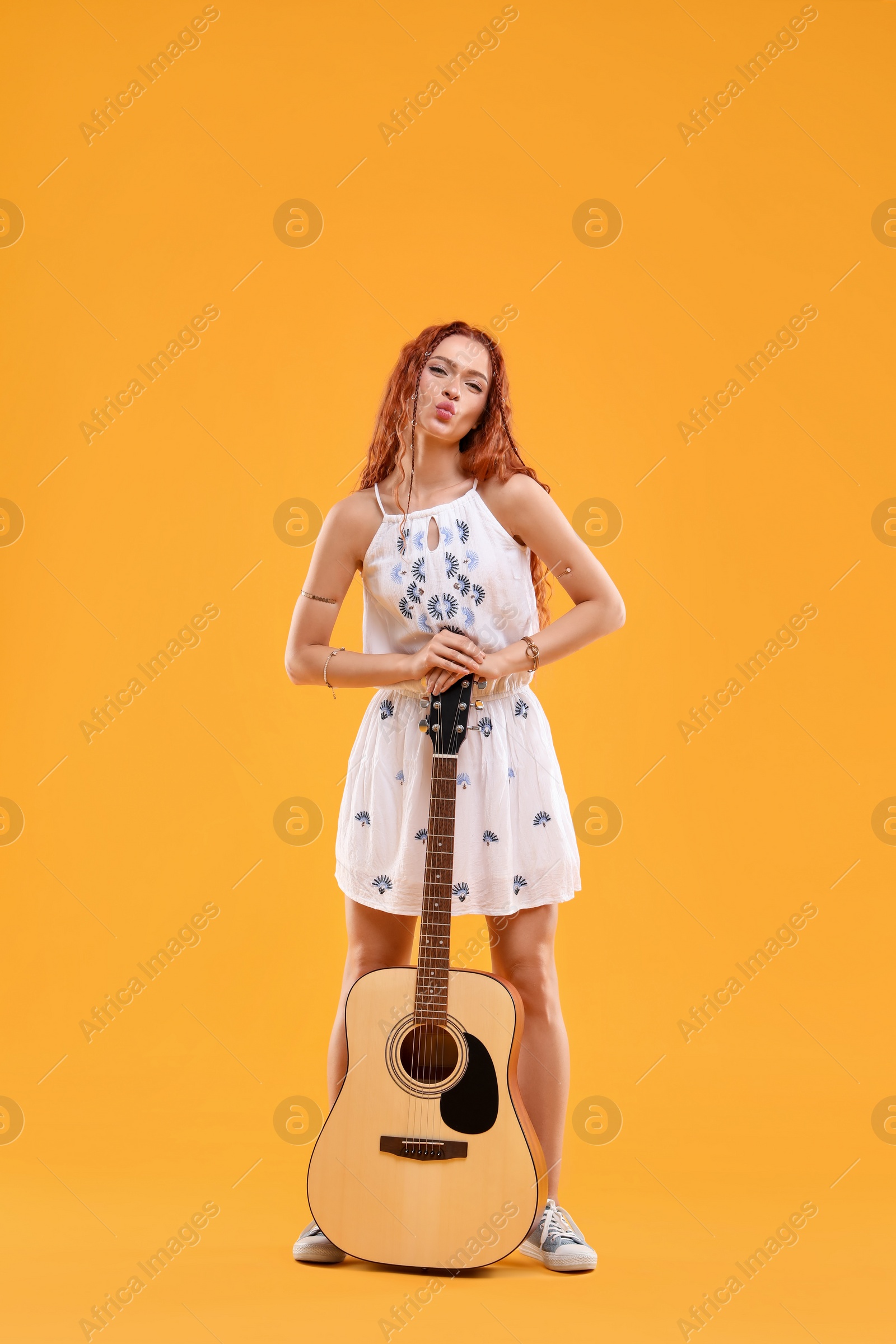 Photo of Beautiful young hippie woman with guitar on orange background