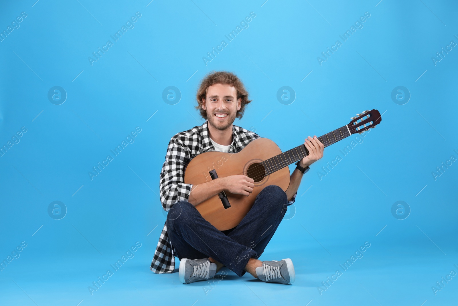 Photo of Young man playing acoustic guitar on color background