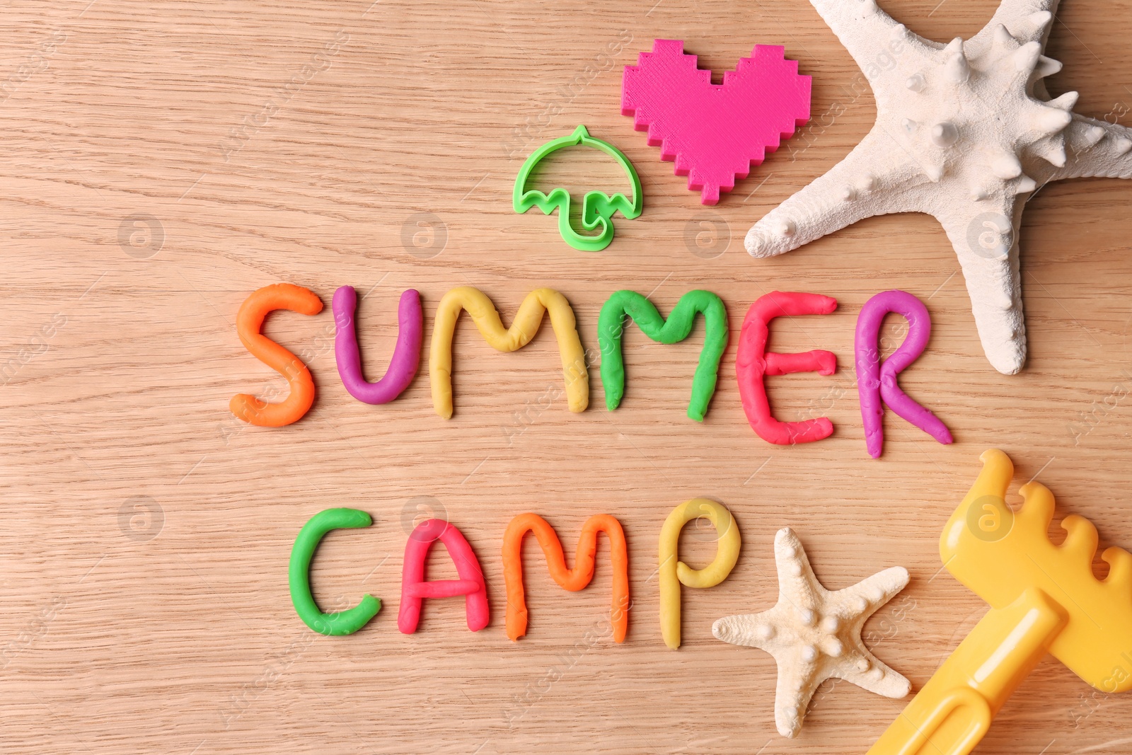 Photo of Text SUMMER CAMP made with play dough on wooden background, top view