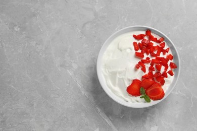 Delicious yogurt served with strawberries on grey marble table, top view. Space for text