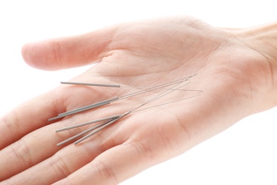 Woman holding needles for acupuncture on white background