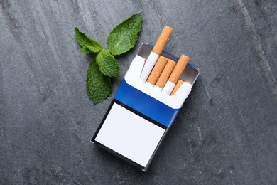 Photo of Pack of menthol cigarettes and mint on grey table, flat lay