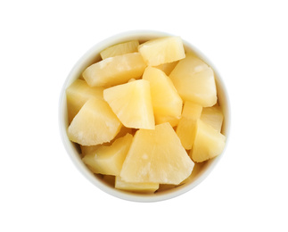 Pieces of delicious canned pineapple in bowl on white background, top view