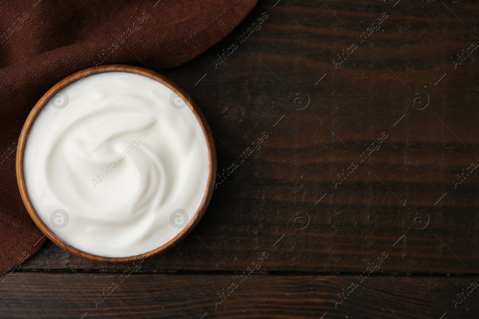 Photo of Delicious natural yogurt in bowl on wooden table, top view. Space for text