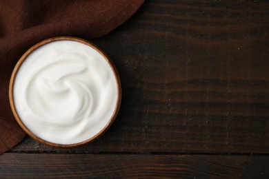 Photo of Delicious natural yogurt in bowl on wooden table, top view. Space for text