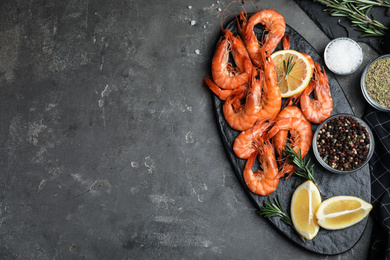 Photo of Delicious cooked shrimps served with rosemary and lemon on dark grey table, flat lay. Space for text