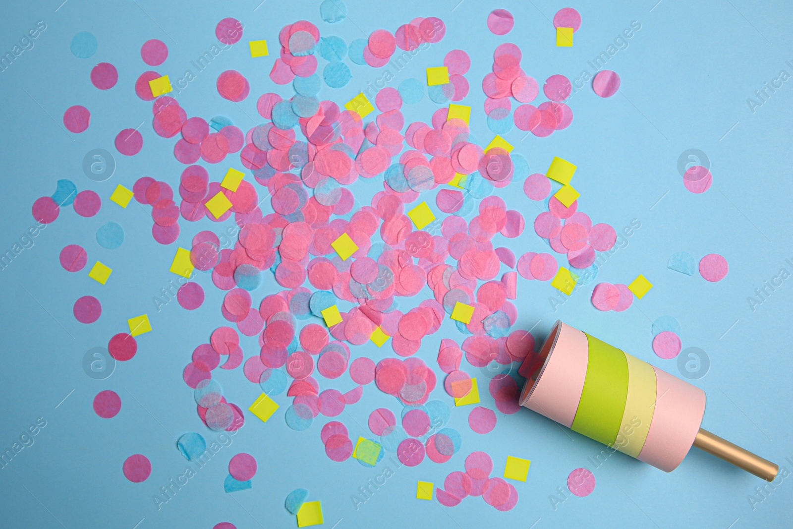 Photo of Party popper with bright confetti on light blue background, flat lay