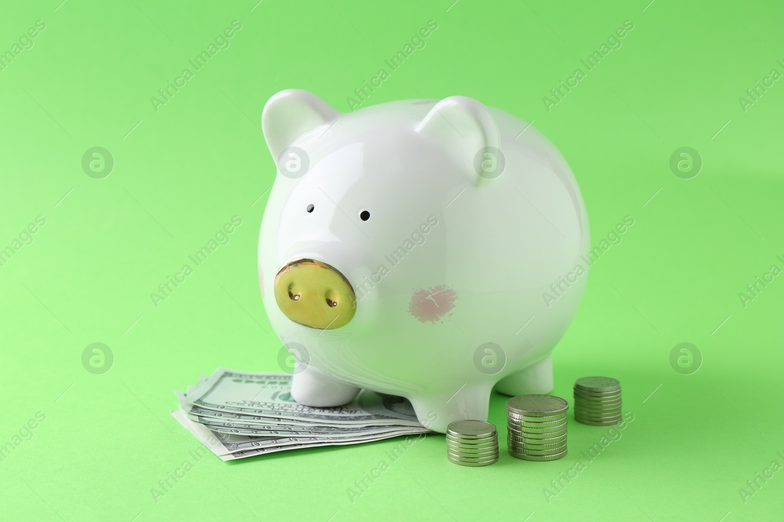 Photo of Financial savings. Piggy bank, dollar banknotes and stacked coins on green background