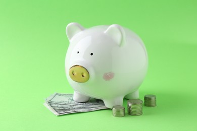 Financial savings. Piggy bank, dollar banknotes and stacked coins on green background