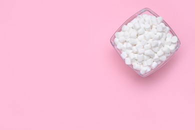 Photo of Bowl of sweet marshmallows on pink background, top view. Space for text