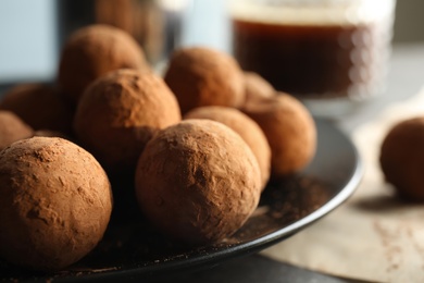 Plate with chocolate truffles on table, closeup