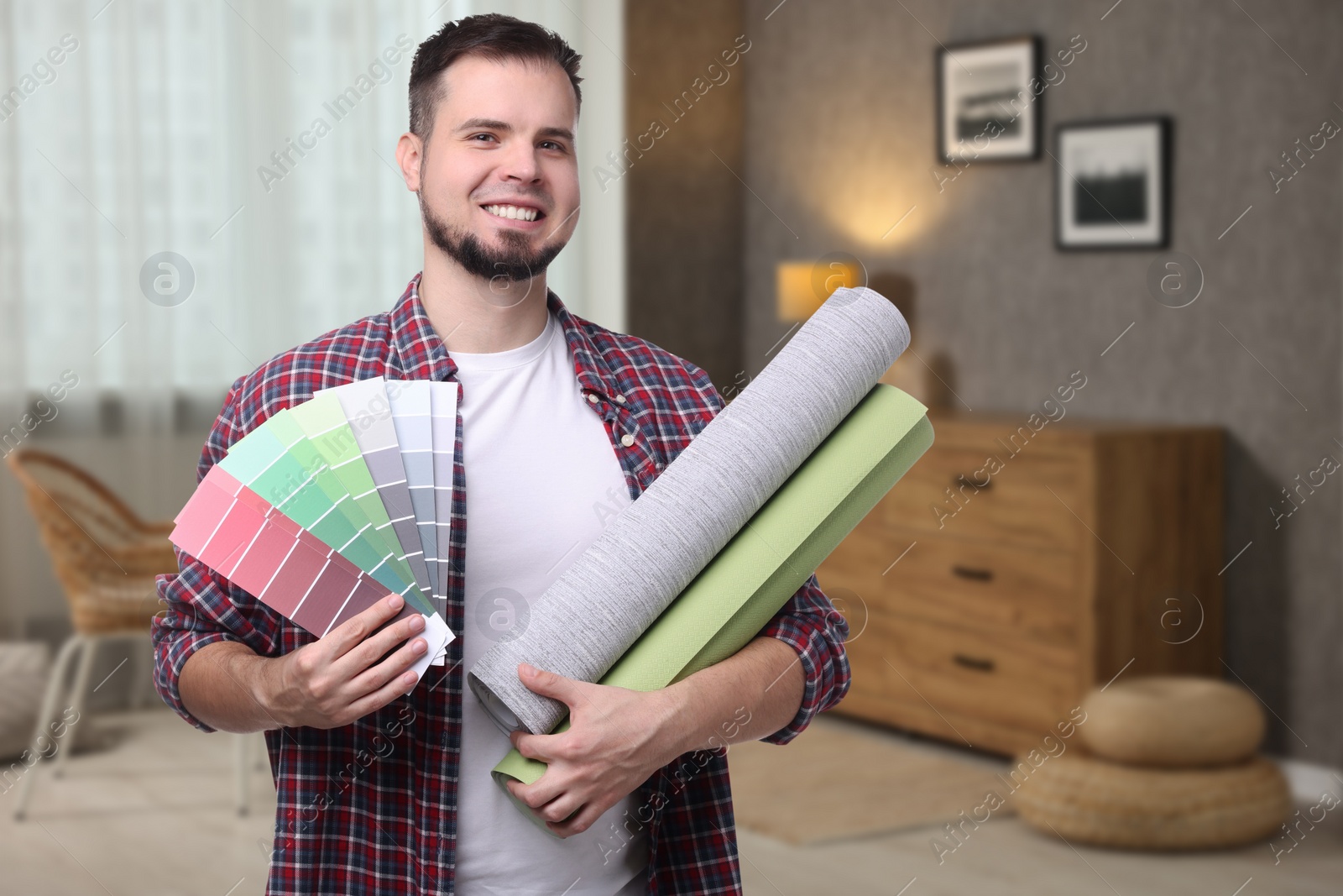Image of Man with wallpaper rolls and color selection chart in room