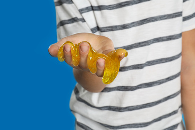 Photo of Little boy with slime on blue background, closeup