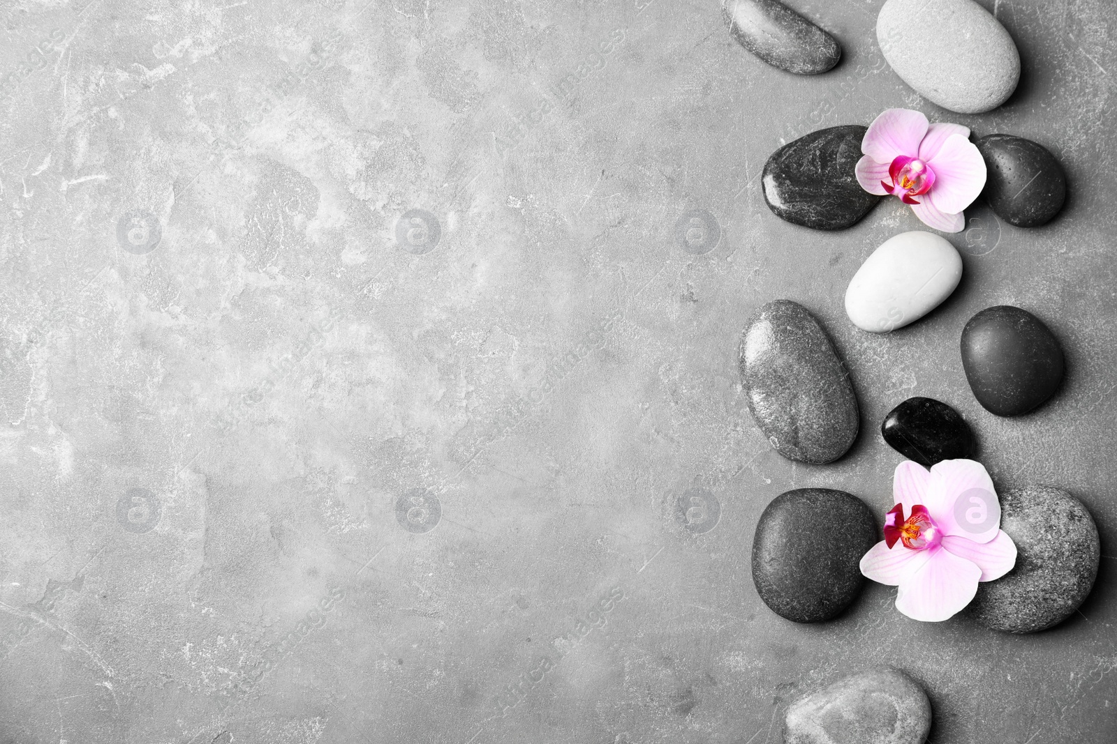 Photo of Stones with orchid flowers and space for text on grey background, flat lay. Zen lifestyle