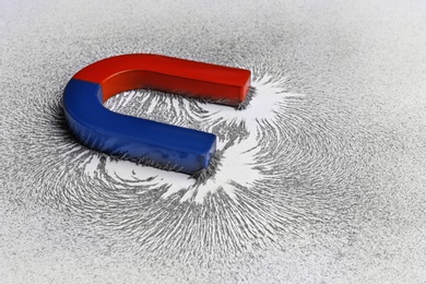 Photo of Red and blue horseshoe magnet with iron filings on white background