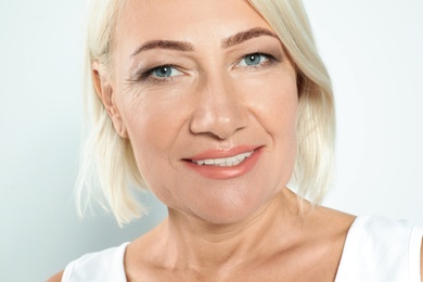 Portrait of mature woman with beautiful face on grey background