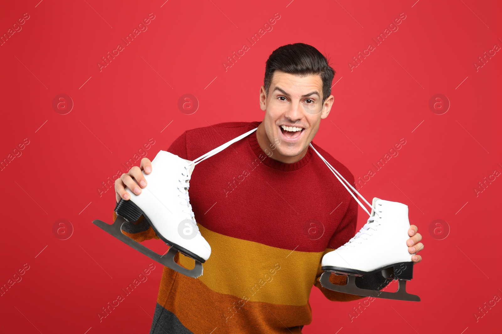 Photo of Emotional man with ice skates on red background