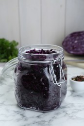 Tasty red cabbage sauerkraut and ingredients on white marble table