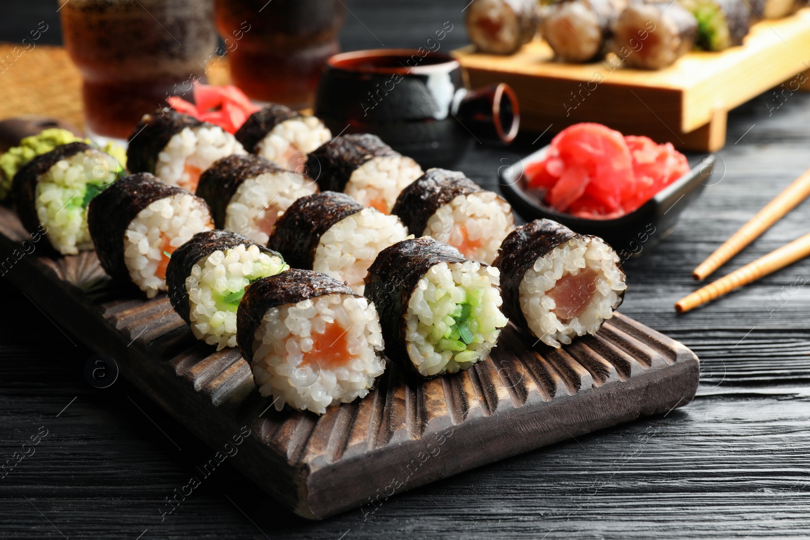 Photo of Tasty sushi rolls served on black wooden table