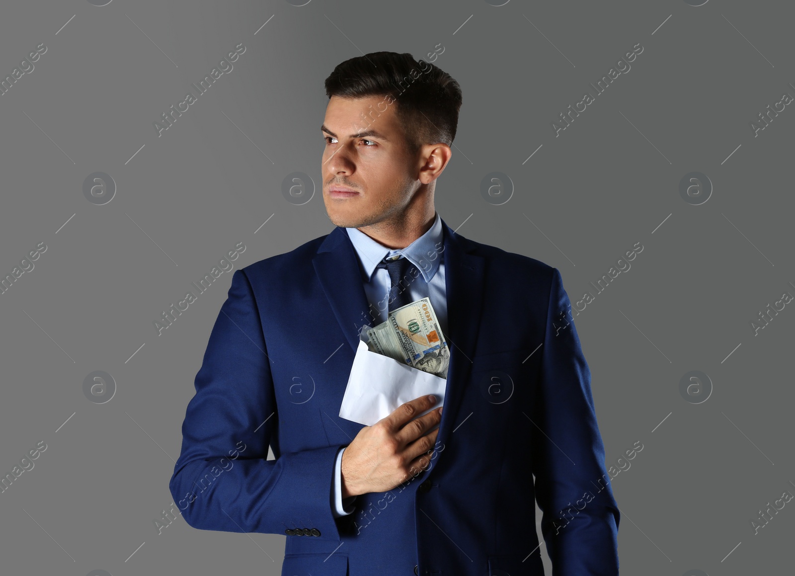 Photo of Man putting bribe into pocket on grey background