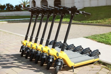 Photo of Many modern electric scooters on city street. Rental service