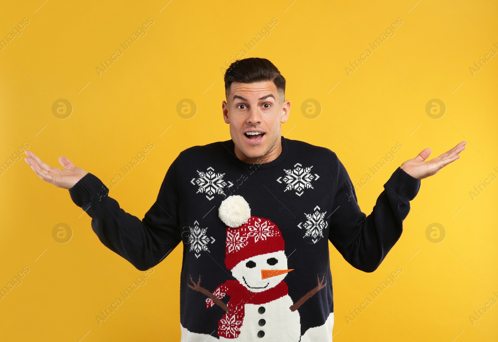 Photo of Surprised man in Christmas sweater on yellow background