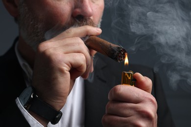 Photo of Bearded man lighting cigar on dark grey background, closeup