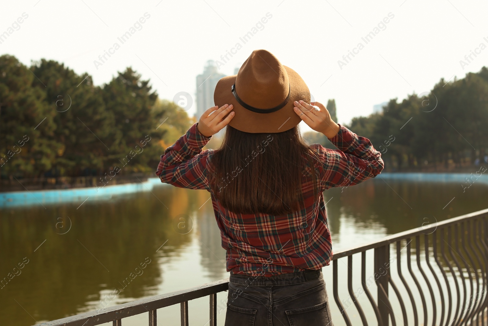 Photo of Young beautiful woman near pond in park. Autumn walk