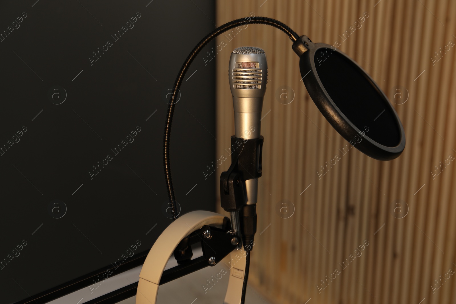 Photo of Stand with microphone, headphones and pop filter indoors. Sound recording and reinforcement