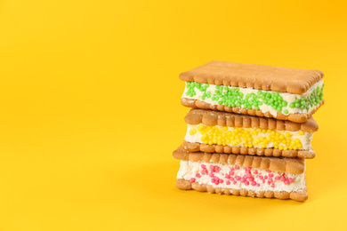 Photo of Sweet delicious ice cream cookie sandwiches on yellow background. Space for text